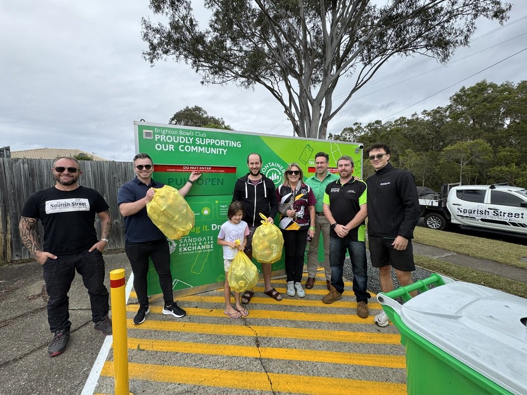 Community members standing beside the Sandgate Bottle & Can Exchange Brighton Bag Drop.
