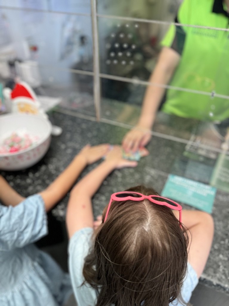 A child receiving a container refund at the Sandgate Bottle & Can Exchange register.