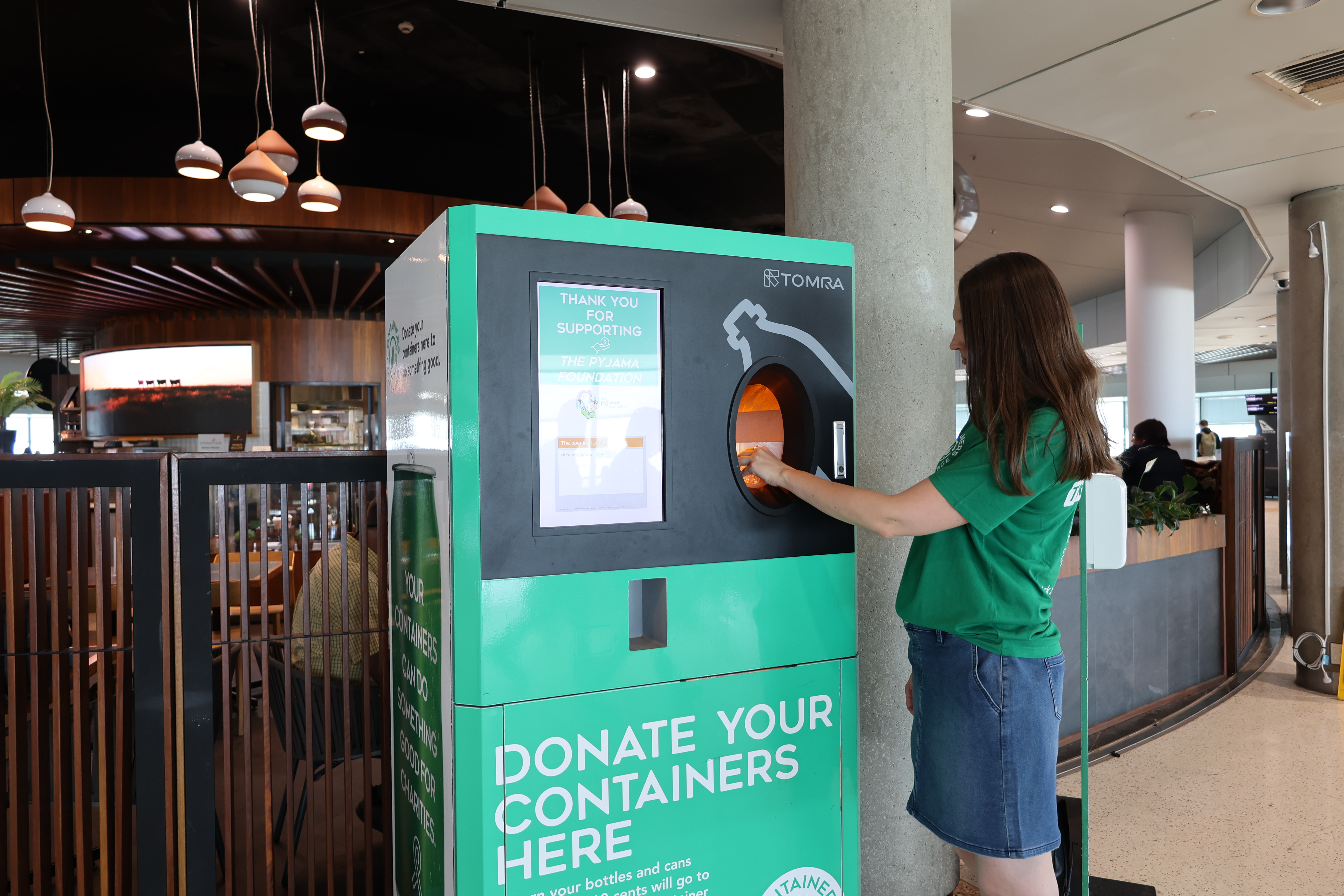 A person donating a container at a Brisbane Airport donation station.