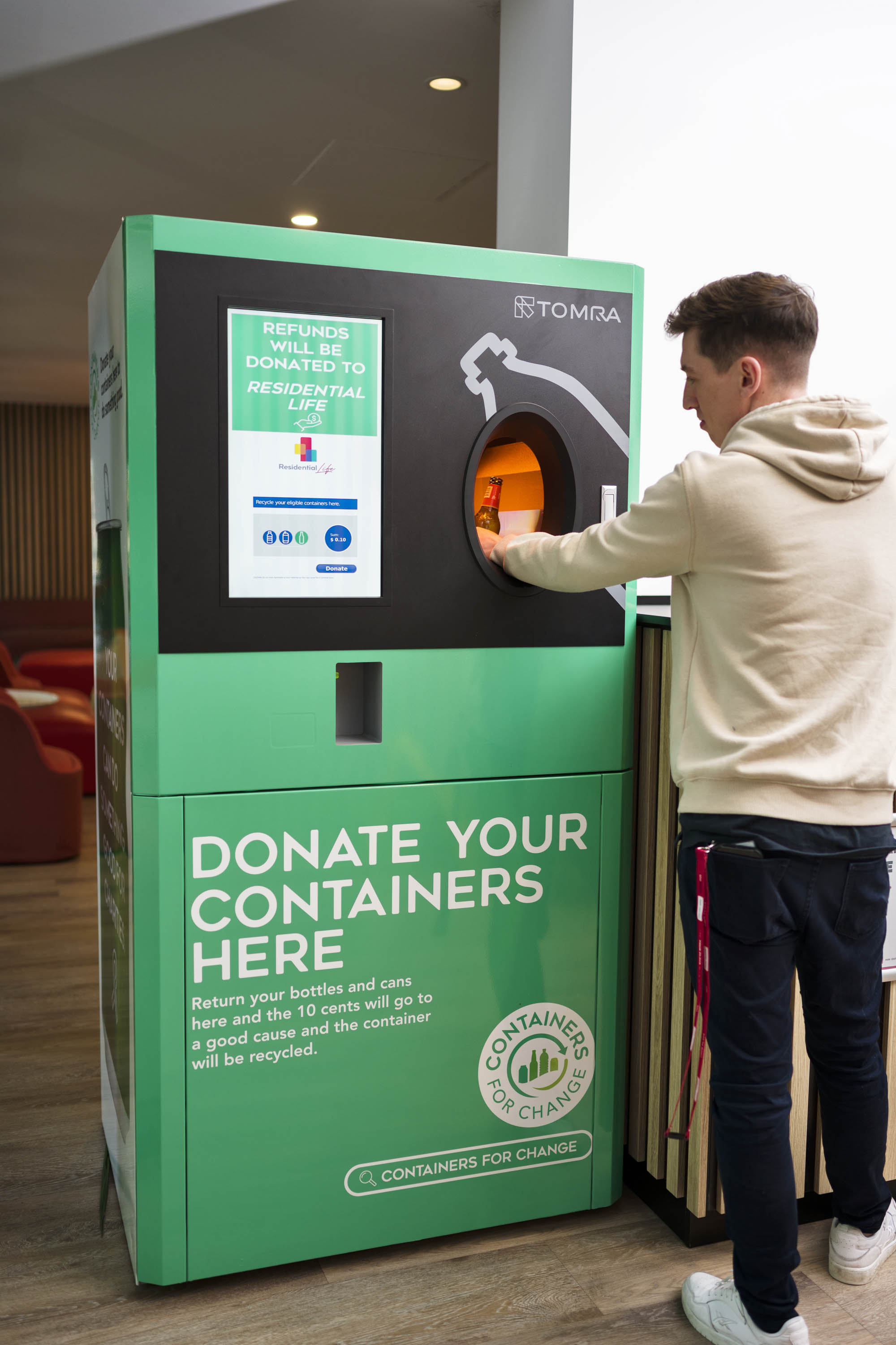 A resident donating a container at a Containers for Change donation station.
